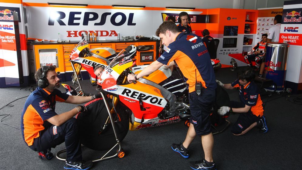 técnicos en el box del equipo repsol realizando el mantenimiento de una MotoGP