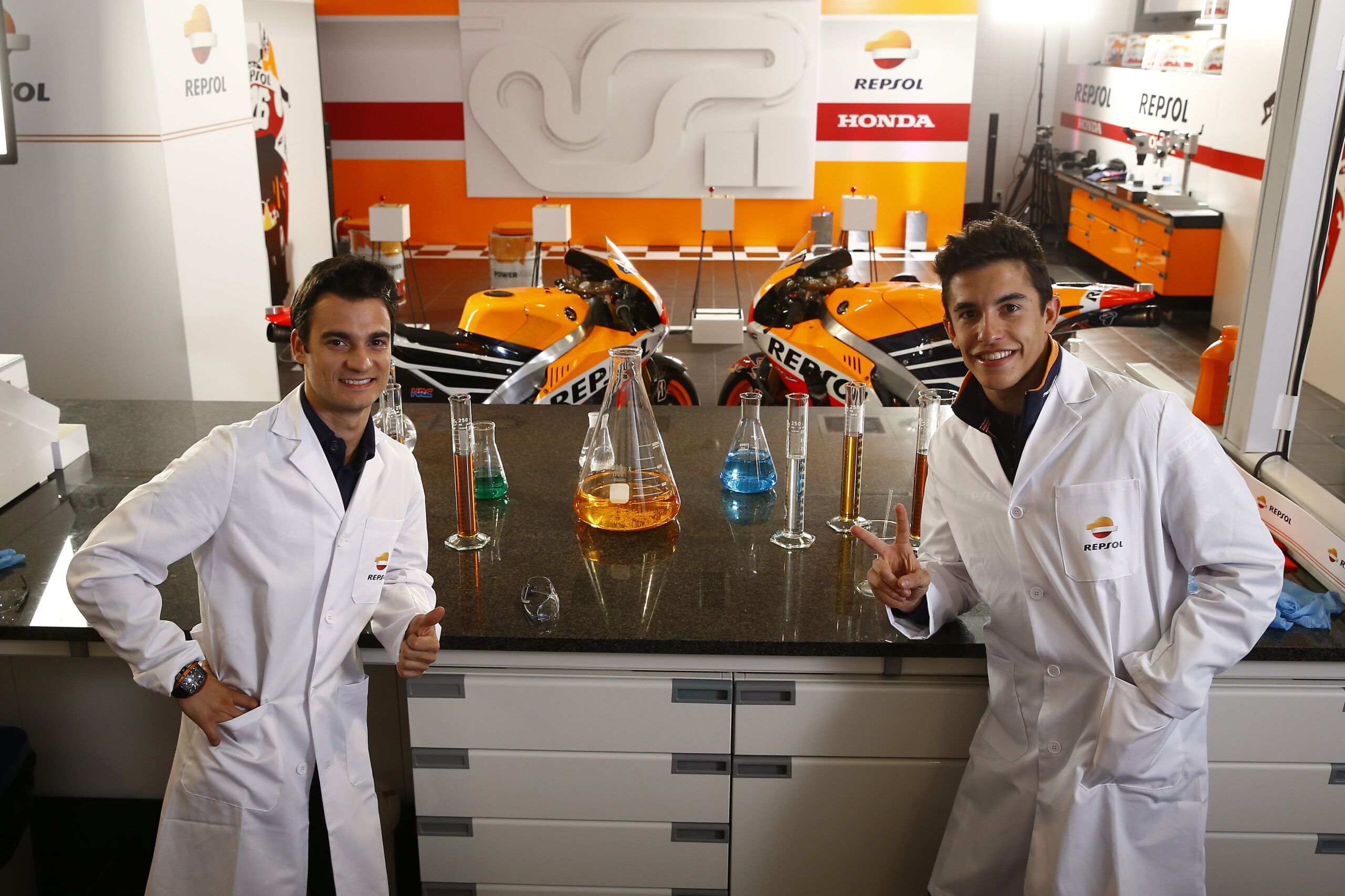 Dani Pedrosa y Marc Márquez vestidos con batas de laboratorio en el Centro de Tecnología Repsol